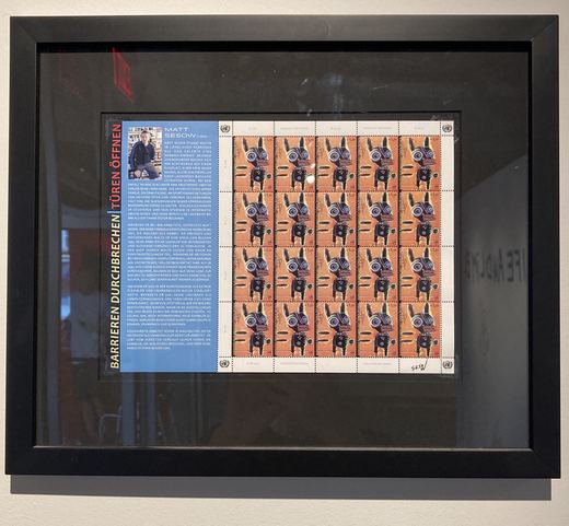 The United Nations stamp sheet with Matt's "Dive Bomb" (2013), framed in the show.