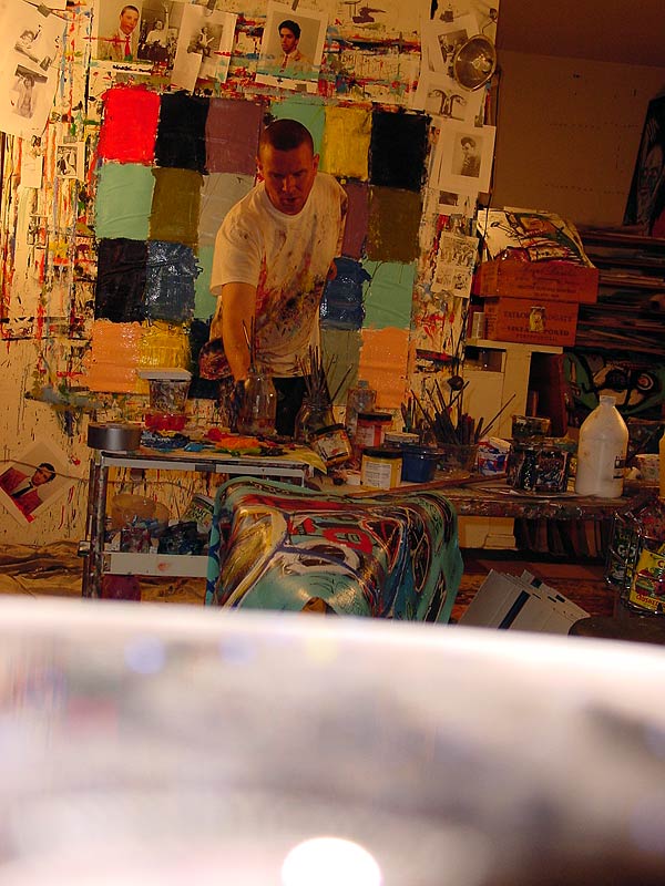 Working on the floor under a lamp, color charts pinned to the wall.